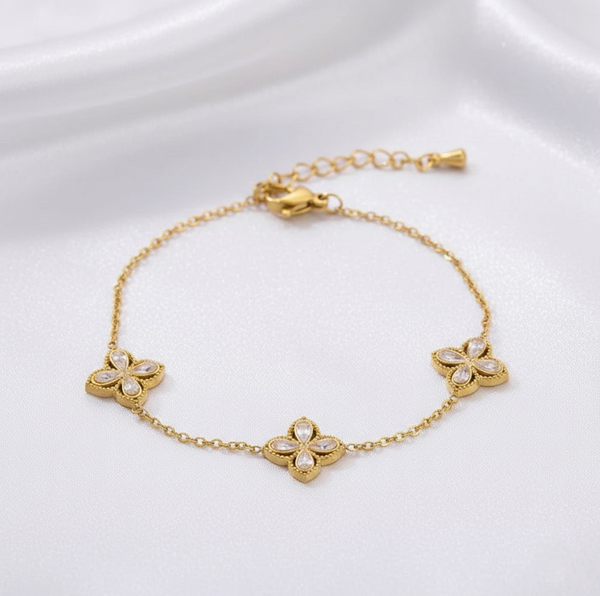 Gold bracelet with floral designs on a white background